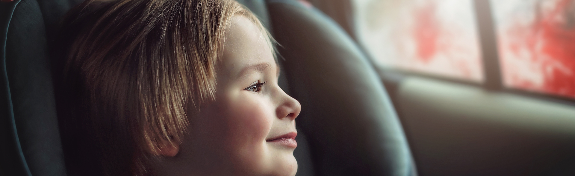 Boy sitting in car smiling and looking out the window
